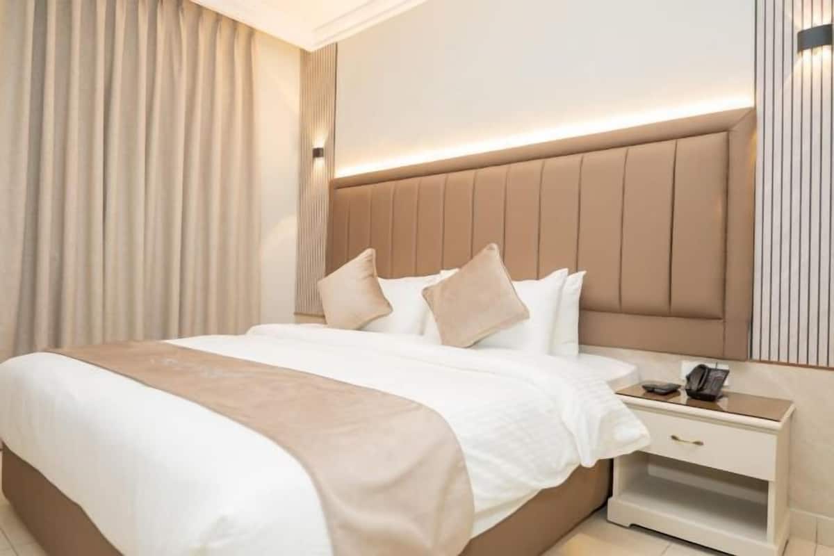 A hotel room with a large bed, a bedside table, and a headboard.
