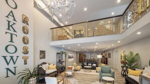 Ampla sala de estar com lustre, diversas opções de assento e uma parede decorativa com letras.