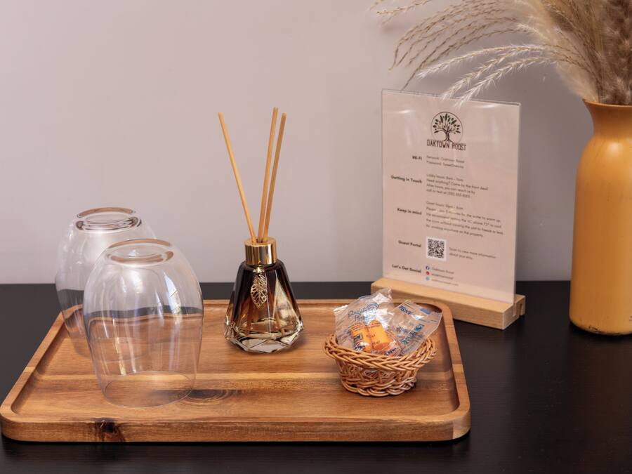 Un plateau en bois avec deux bouteilles en verre, un diffuseur à bâtonnets et un panier en osier contenant des bougies.