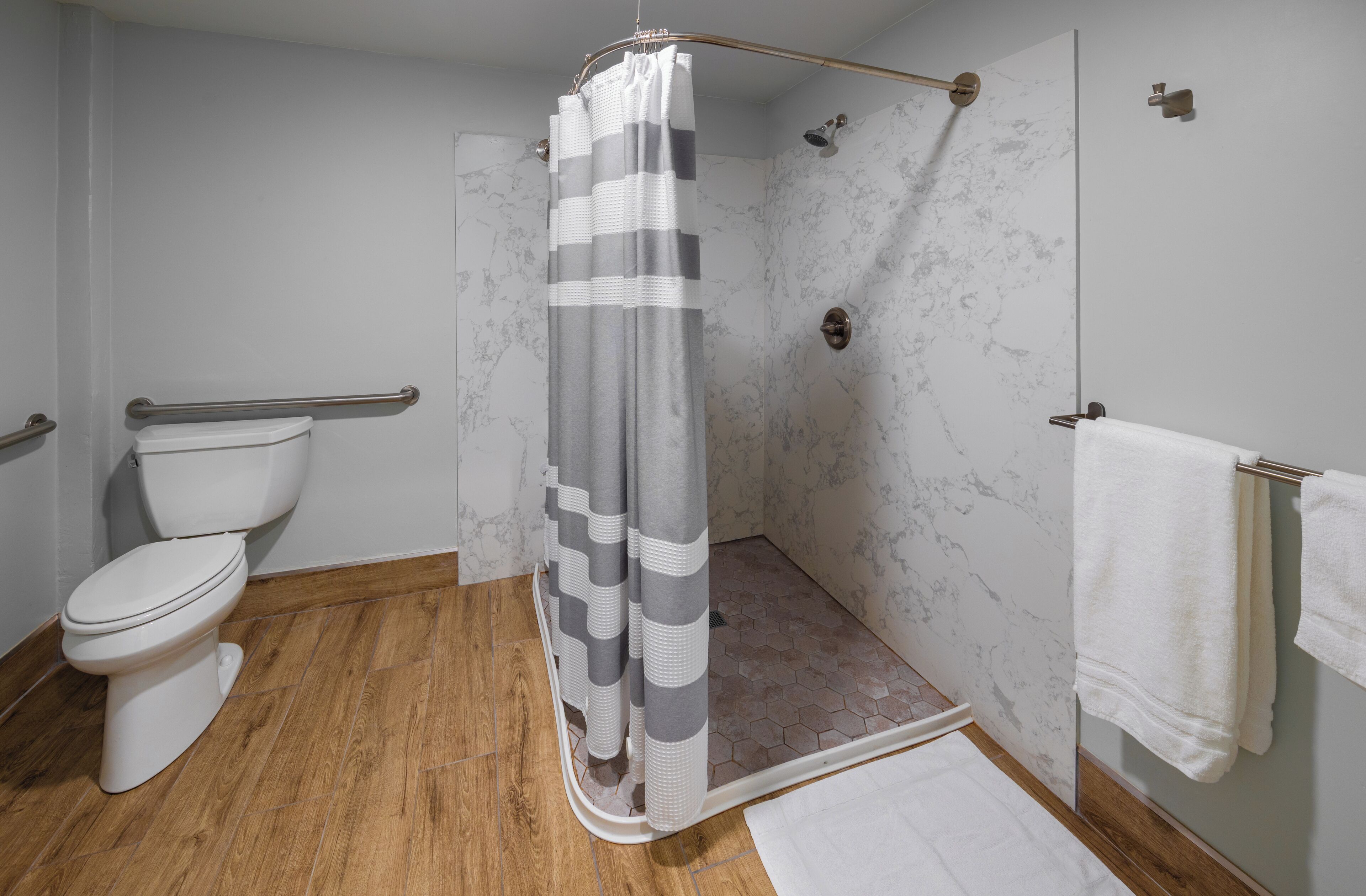 Une salle de bain équipée d’une douche, de toilettes et d’une barre d’appui.