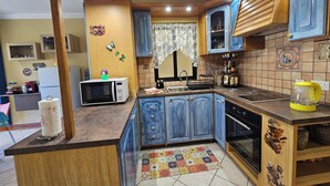 A kitchen with wooden cabinets, a microwave, a stove, and a sink. - Country View Apartment (Mellieha)