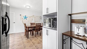 A modern kitchen with white cabinets, a wooden dining table, and a small island with a toaster. - Villa Pausa - 3 bedroom house in Gurabo (Gurabo)