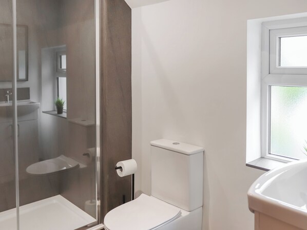 A modern bathroom with a glass shower enclosure, a toilet, and a sink. - 2 bedroom accommodation in Conwy (Conwy)
