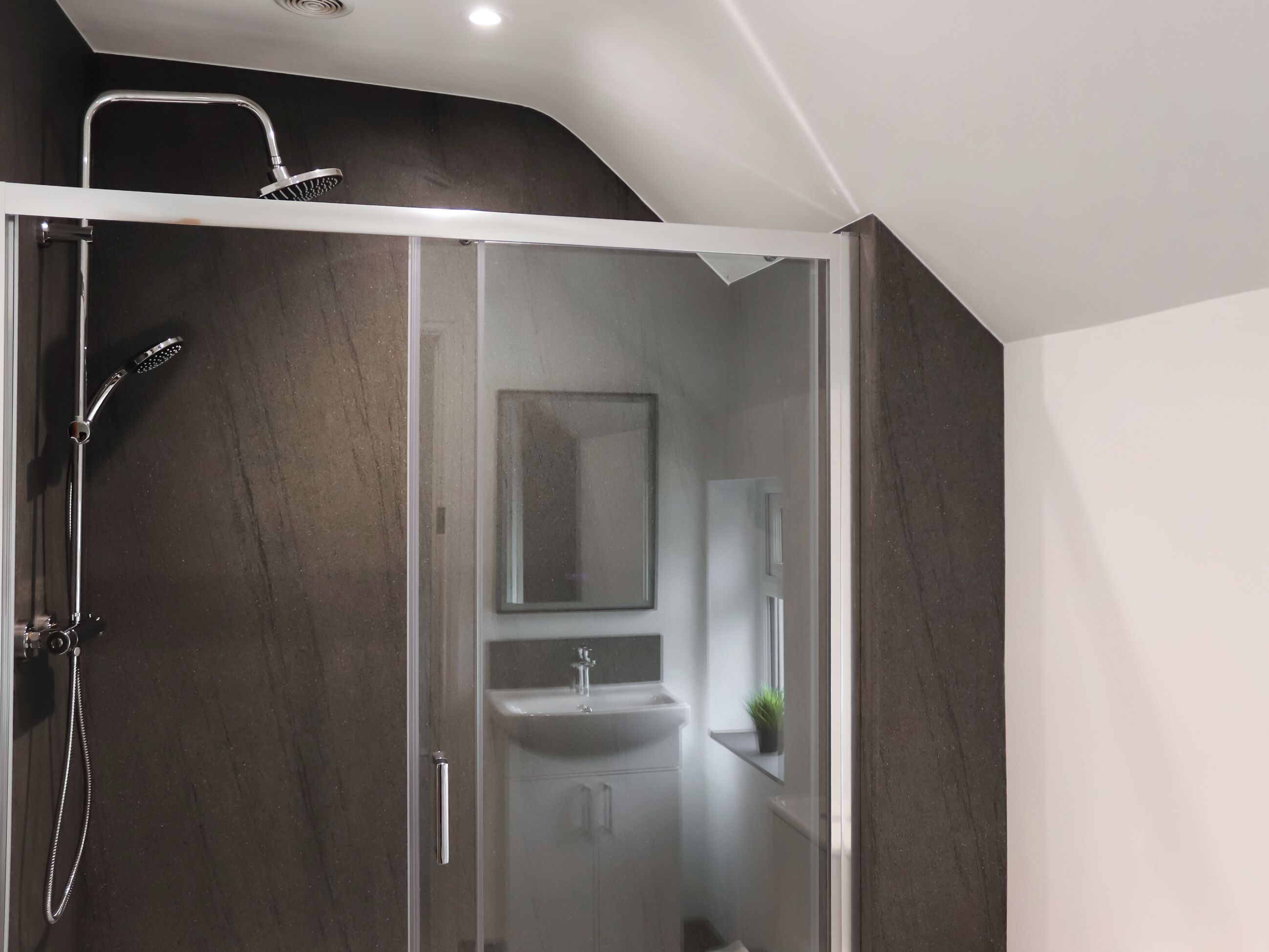 A modern bathroom with a glass-enclosed shower, a sink, and a mirror above it.