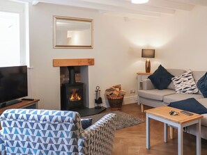 A living room with a fireplace, a sofa, a TV, and a small table.