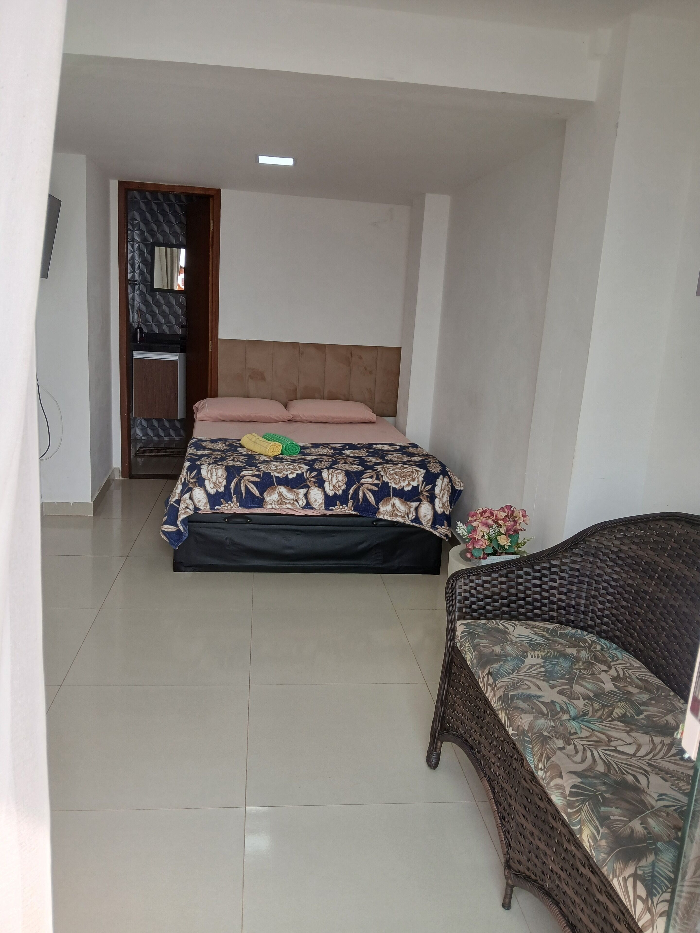 A bedroom with a bed, a sofa, and a small table with flowers.