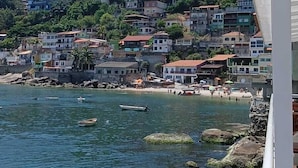 A coastal town with buildings on a hillside, boats in the water, and a clear sky. - Pousada ilha Bella  (Rio de Janeiro)
