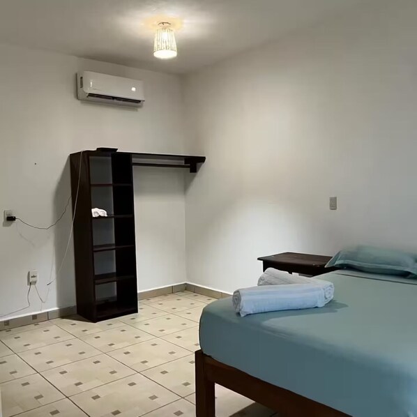 A bedroom with a bed, a bedside table, a wardrobe, and an air conditioning unit.