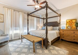 A four-poster bed with a wooden canopy, a bench, a dresser, and a chair in a bedroom with a patterned rug. - Anchor & Oar Cottage (Tullahoma)