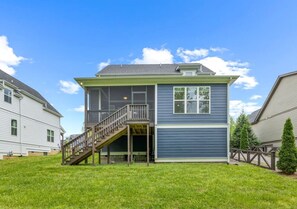 A two-story house with a covered porch and a staircase leading to a deck. - Anchor & Oar Cottage (Tullahoma)