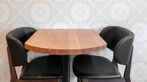 A round wooden table with black chairs.