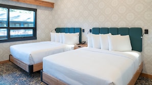 A hotel room with two beds, a large window, and patterned wallpaper.