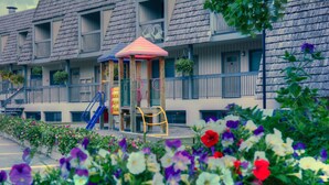 A building with a playground, including a slide and swings, and a small pavilion.