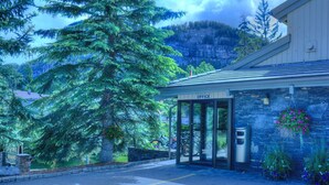 A building labeled "OFFICE" with a glass door entrance, a stone wall, and a mountain backdrop.