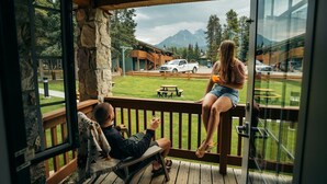 Une terrasse en bois avec des murs en pierre, une vue sur une montagne et un camionnette blanche garée à l’extérieur.