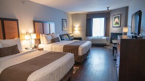 A hotel room with two beds, a desk, a chair, a television, and a window with curtains. - Mountain Getaway with Free Breakfast (Canmore)