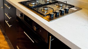 Una cucina con piano cottura a gas, pensili neri e piano di lavoro bianco.