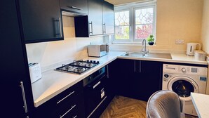 Una cucina moderna con mobili scuri, un piano cottura a gas, un forno a microonde, un lavello e una lavatrice.