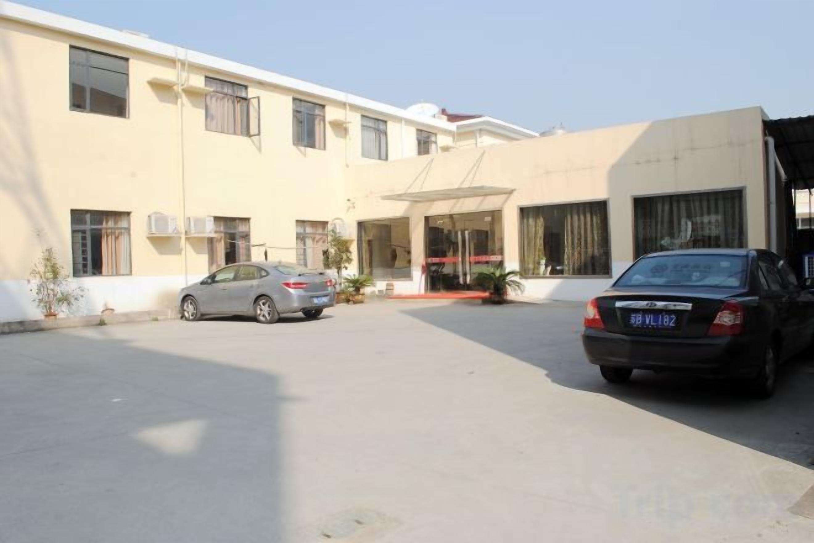 Un edificio con un'area di parcheggio e due automobili parcheggiate davanti.