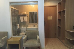 A bathroom with a shower, toilet, sink, and a chair. - Lexin Business Hotel (Wuxi)