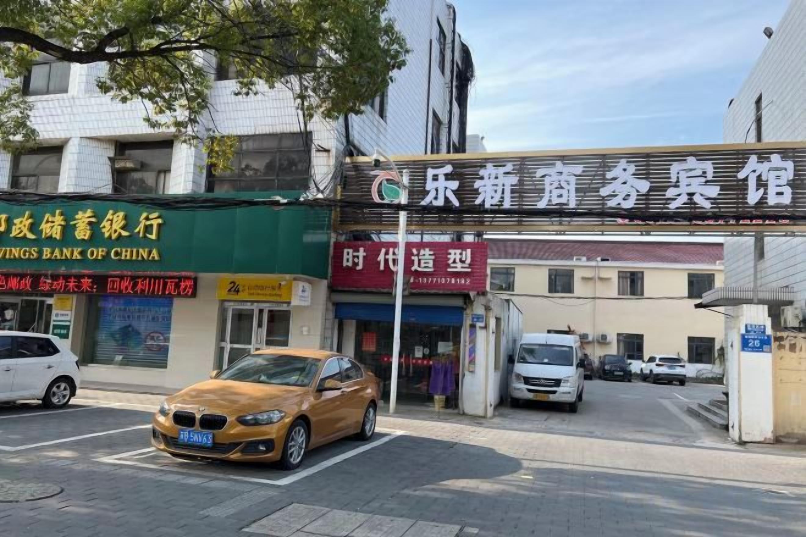 A street view with a bank, a cinema, and a car parked in front.
