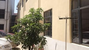 A building with a tree in front, a metal pole, and a window. - Lexin Business Hotel (Wuxi)