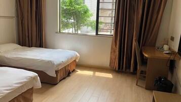 A room with two beds, a desk, and a window with curtains.