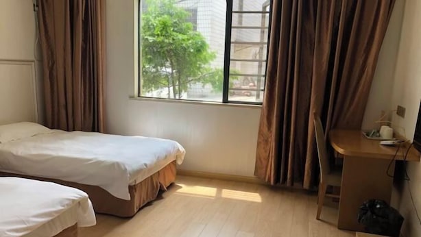 A room with two beds, a wooden desk, and a window with curtains. - Lexin Business Hotel (Wuxi)