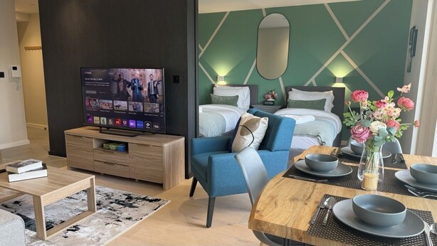 A modern hotel room with a TV, a sofa, a bed, and a dining area. - Luxury Manchester City Centre Apartment (Manchester)