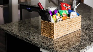 Un comptoir de cuisine sur lequel se trouve un panier en osier contenant des en-cas et une bouteille de vin.