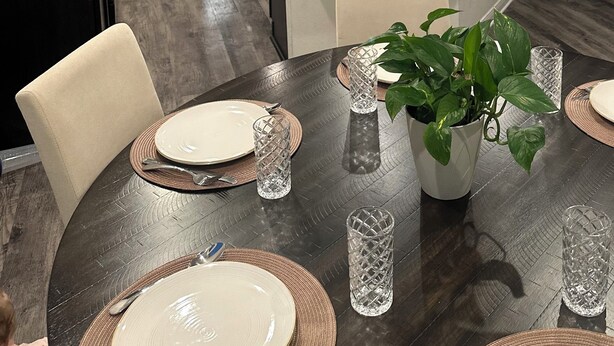 Une cuisine moderne dotée d’un îlot central, d’appareils électroménagers en acier inoxydable et de luminaires suspendus.