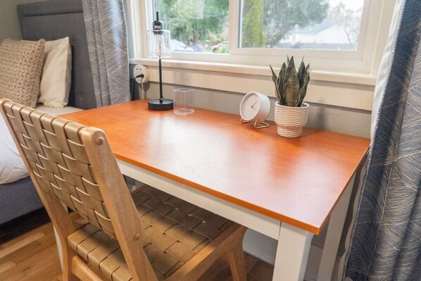 A wooden dining table with a white base, a clear glass container, a white clock, and a potted plant. - Large Tacoma Stay, Pet Friendly, Centrally Located, Parking, A/C units (Tacoma)