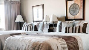A hotel room with a large bed, two bedside tables with lamps, a framed picture on the wall, and a decorative wall piece. - Marcus Daly Motel (Anaconda)