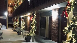 A building with a covered outdoor area decorated with lights and garlands, featuring a staircase and potted plants. - Marcus Daly Motel (Anaconda)