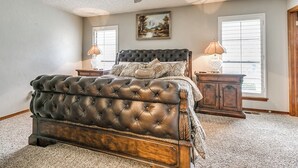A bedroom with a tufted headboard bed, two bedside tables with lamps, a ceiling fan, and a window with blinds. - Spacious 5-bedroom house with AC, WiFi in phenomenal Oklahoma City (Oklahoma City)