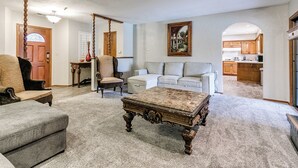 A spacious living room with a large, ornate coffee table, a comfortable sofa, and a dining area visible through an archway. - Spacious 5-bedroom house with AC, WiFi in phenomenal Oklahoma City (Oklahoma City)