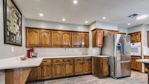A modern kitchen with wooden cabinets, a stainless steel refrigerator, and a red stand mixer. - Spacious 5-bedroom house with AC, WiFi in phenomenal Oklahoma City (Oklahoma City)