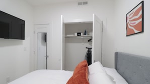 A hotel room with a bed, a grey headboard, a white wall, a mounted TV, and a door leading to a closet. - Unit 2: Cozy 1-Bed in the heart of Dc (Washington)