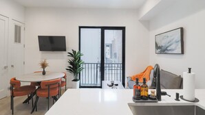A modern kitchen with a dining area, a large window, and a flat-screen TV. - Unit 4: Studio / Queen+Sofa Bed|DC Convention Centre (Washington)