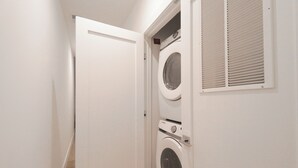 Une buanderie équipée de deux machines à laver à chargement frontal et d’un sèche-linge à évacuation.