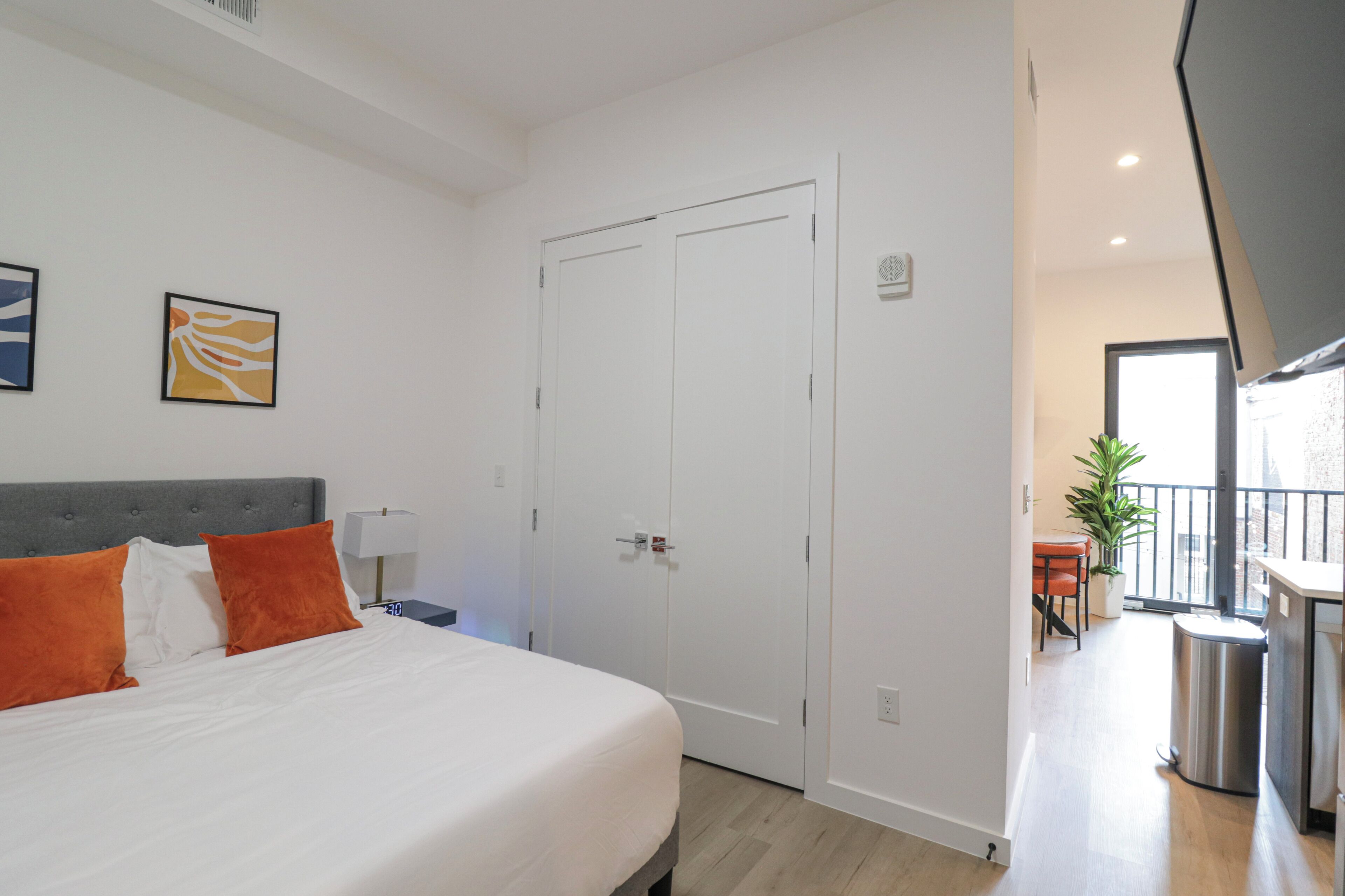 Une chambre à coucher avec un lit, une table de chevet, une lampe et une porte.
