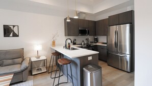 A modern kitchen with a central island, stainless steel appliances, and a minimalist design. - Unit 6: Studio /Queen +Sofa Bed in the heart of DC (Washington)