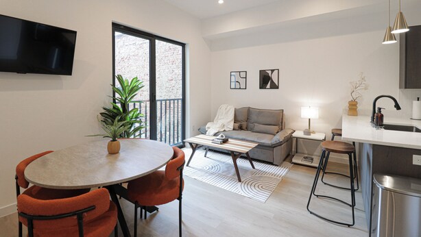 A modern apartment with a dining area, a sofa, a kitchen, and a large window. - Unit 6: Studio /Queen +Sofa Bed in the heart of DC (Washington)