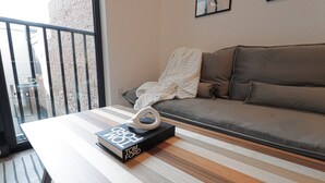 A modern living room with a striped sofa, a glass door leading to a balcony, and a book titled "Tom Ford" on a wooden coffee table. - Unit 6: Studio /Queen +Sofa Bed in the heart of DC (Washington)
