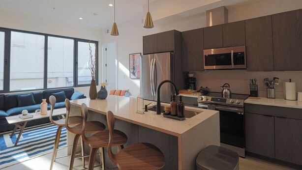 A modern kitchen with a central island, stainless steel appliances, and a dining area with wooden chairs. - Unit 7: Spacious 3BR+Sofa bed | Sleeps 10 (Washington)