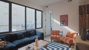 A modern living room with a sofa, armchairs, a coffee table, and a large window. - Unit 7: Spacious 3BR+Sofa bed | Sleeps 10 (Washington)