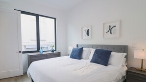 A bedroom with a large bed, a nightstand, a dresser, and a window with a view. - Unit 7: Spacious 3BR+Sofa bed | Sleeps 10 (Washington)