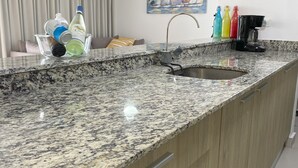 Une cuisine dotée d’un plan de travail en granit, d’un évier encastré et de meubles de rangement en bois.
