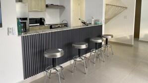 Une cuisine moderne dotée d’un îlot central intégré, de tabourets de bar et d’un luminaire suspendu.