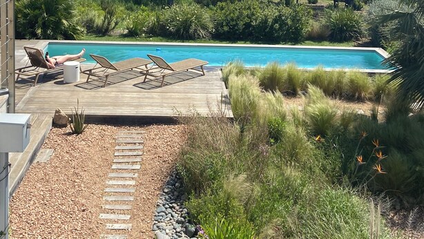 A pool area with lounge chairs and a wooden deck.